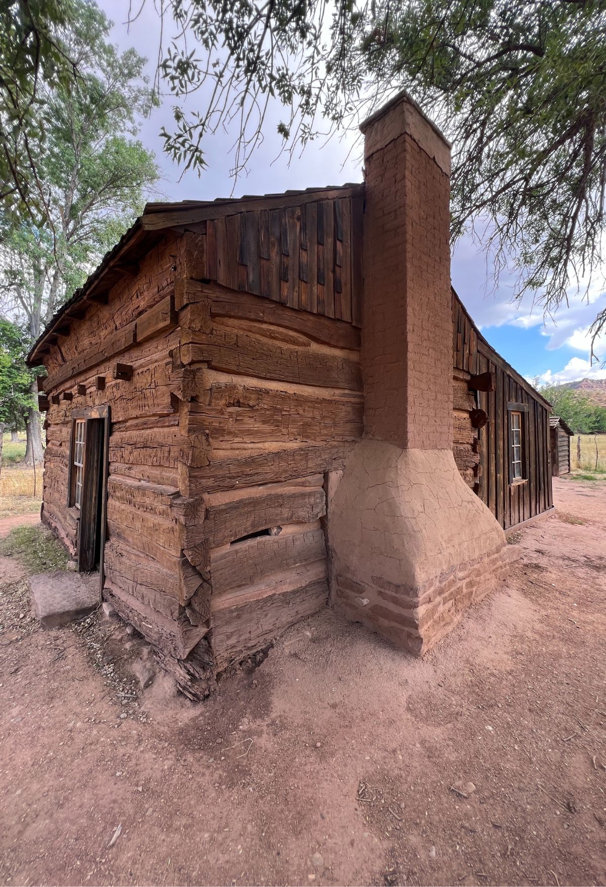 A log cabin with a chimney in the middle of the desert.