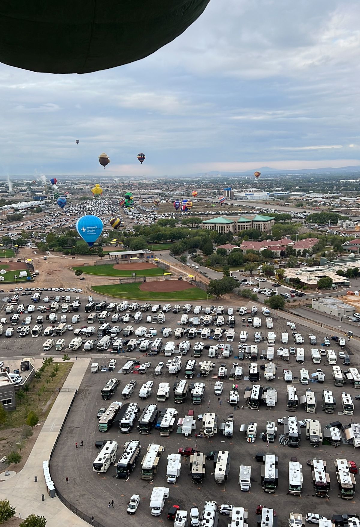 Hot air balloons flying over a parking lot.