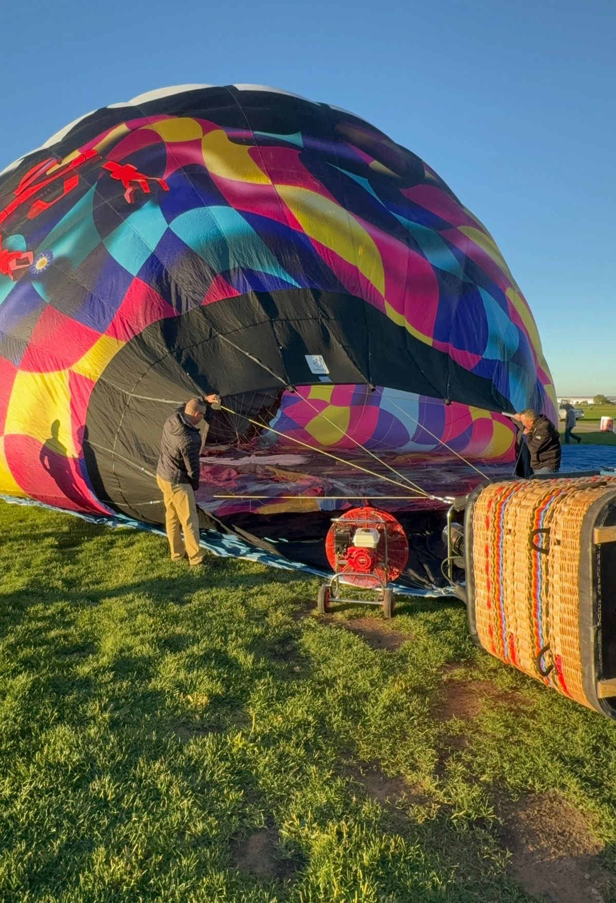 A hot air balloon is being inflated on a grassy field.