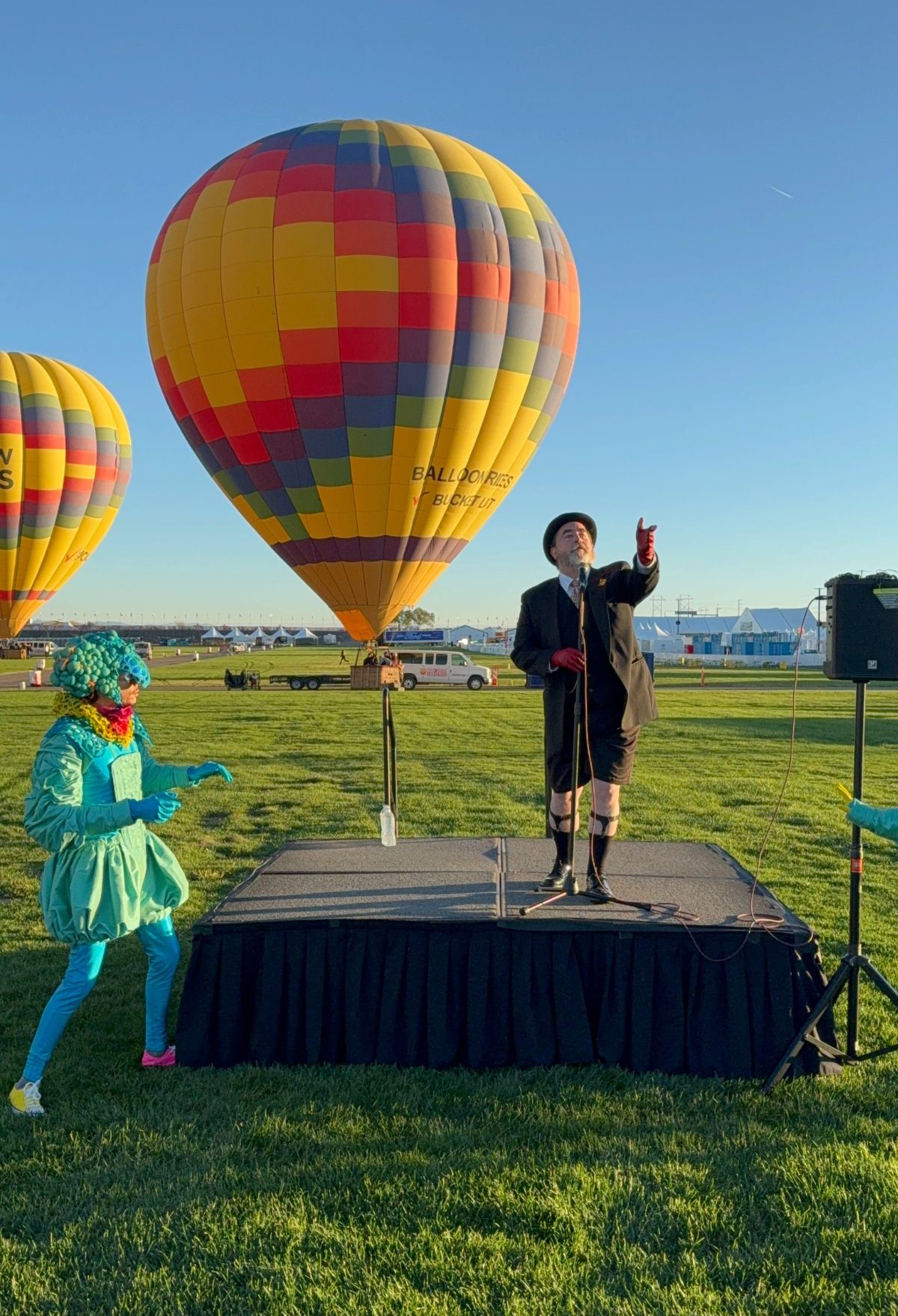 A group of people standing on a stage with hot air balloons in the background.