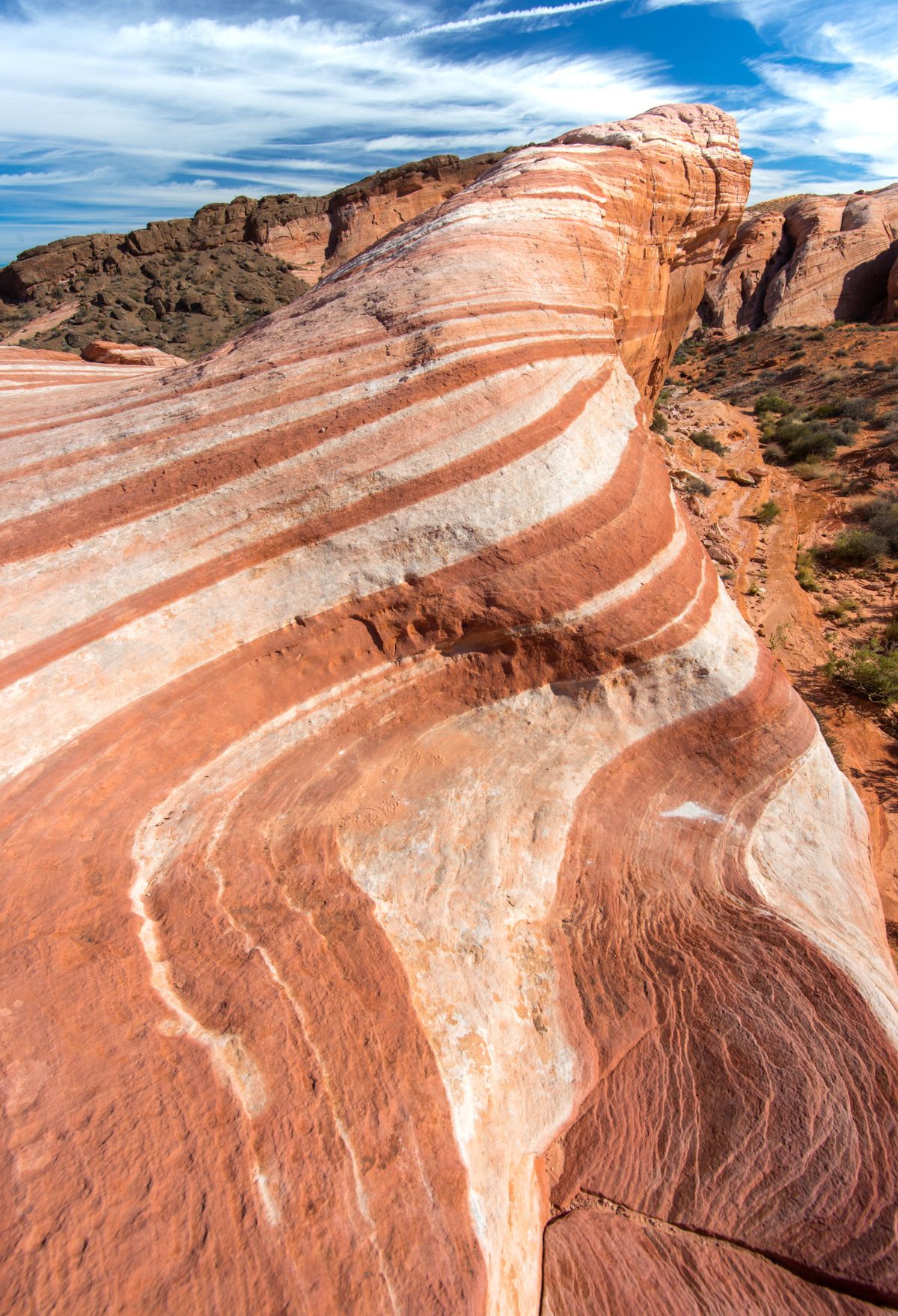 A red and white striped rock formation in Nevada, resembling the vast landscapes found in Utah's national parks.