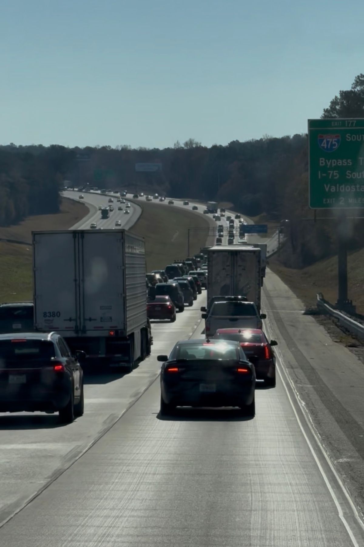 Cars, trucks, and RVs are in heavy traffic on a highway under clear skies, with a green exit sign for I-475 South and I-75 South visible—drivers may be mindful of RV fuel costs on their journey.