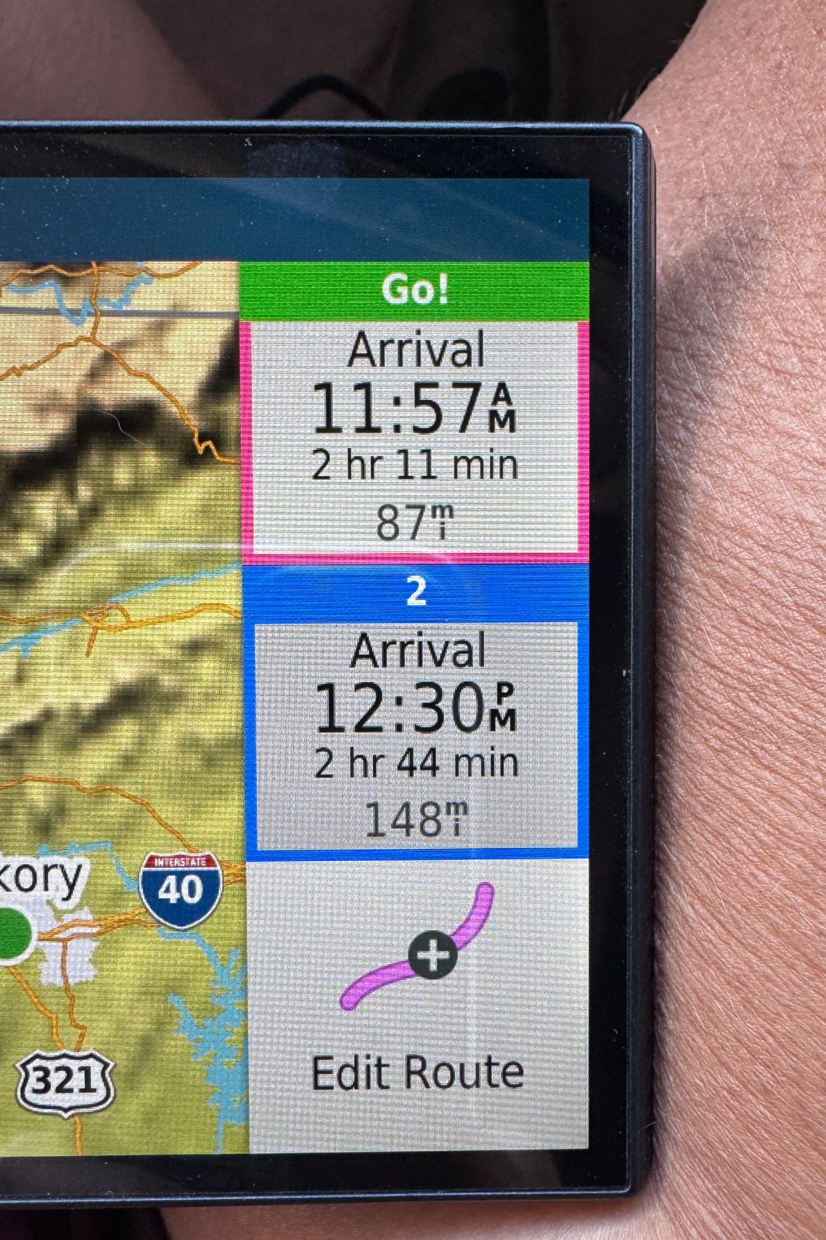A GPS screen displays two route options with RV fuel costs in mind: one arriving at 11:57 AM in 2 hr 11 min (87 miles), and another at 12:30 PM in 2 hr 44 min (148 miles).