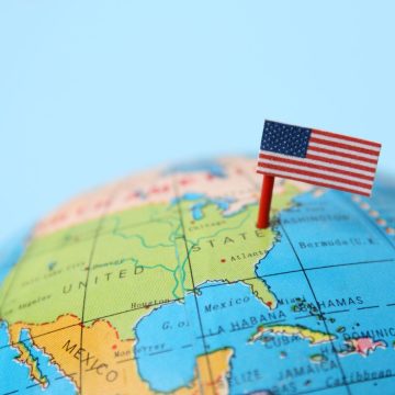 A small American flag on a pin marks the United States on a globe, with surrounding countries and the Atlantic Ocean visible—an inspiring image for those dreaming of full-time RV living across America.