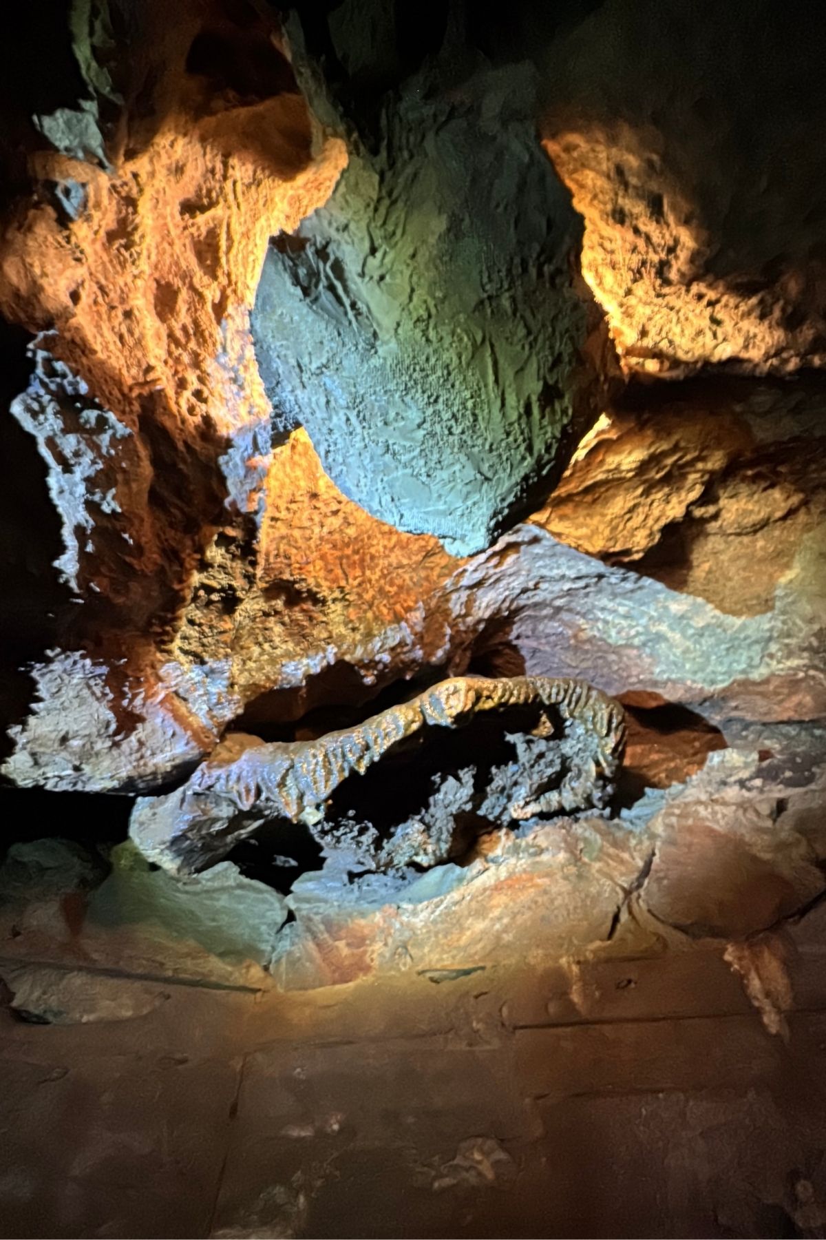 Rocky cave ceiling illuminated by warm and cool artificial lights, highlighting rough textures and varying colors of the stone surface—reminiscent of the unique landscapes found at Green Mountain Thousand Trails.