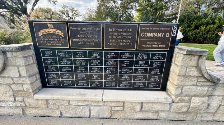 Stone memorial plaque dedicated to Southeast Kansas military veterans, listing names under various organizations, with trees and sky visible in the background.