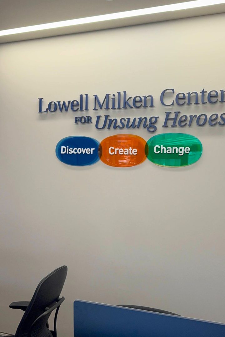Wall sign reads "Lowell Milken Center for Unsung Heroes" above three colored ovals labeled "Discover," "Create," and "Change." Office chairs are visible in the foreground, highlighting this inspiring space in Southeast Kansas.