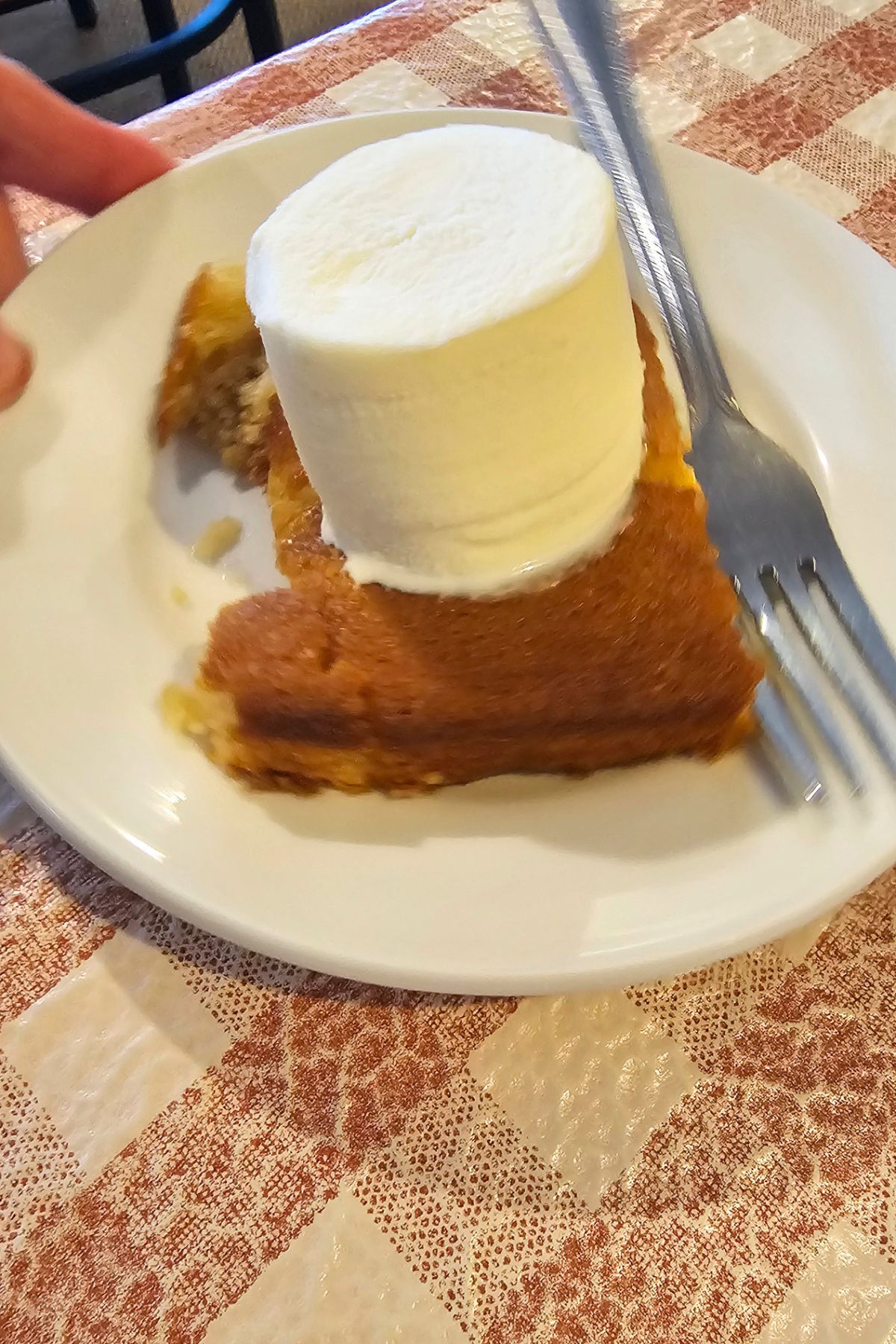 A slice of cake with a cylindrical scoop of vanilla ice cream on top, served on a white plate with a fork—a classic Southeast Kansas dessert presentation.
