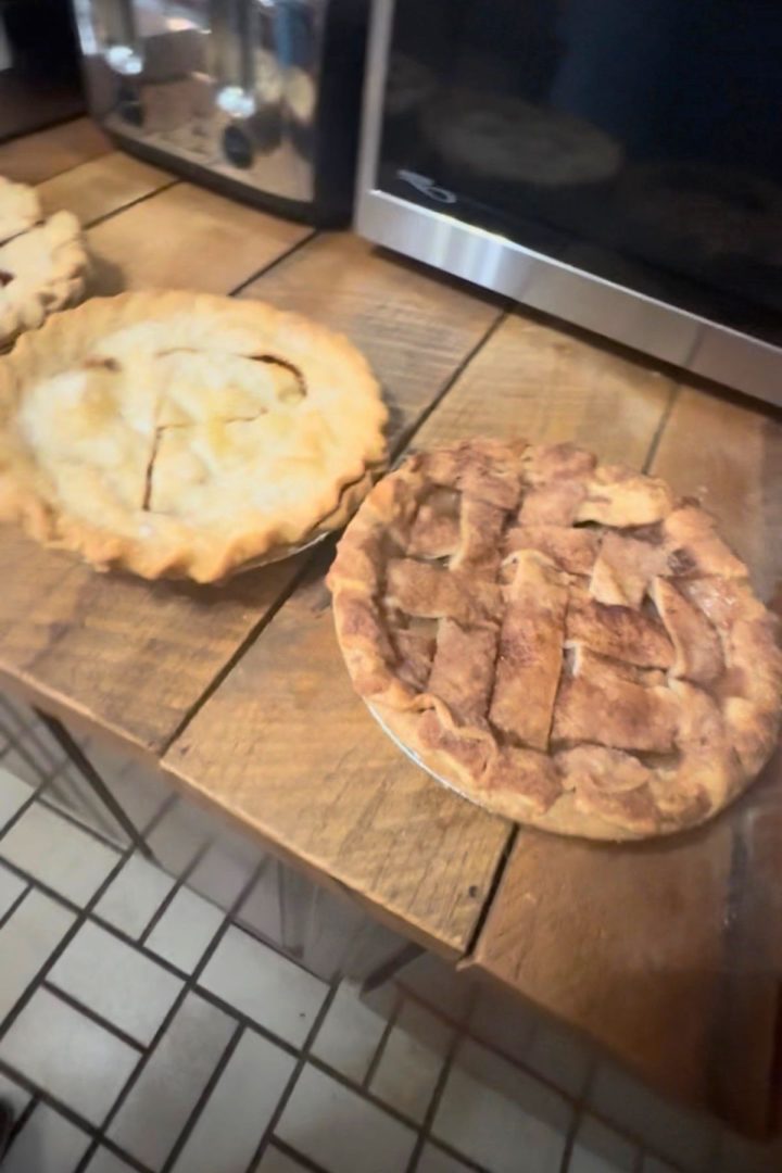 Two homemade pies rest on a wooden counter, one with a solid crust and the other with a lattice top, bringing a touch of Southeast Kansas charm to the kitchen scene near cozy appliances.
