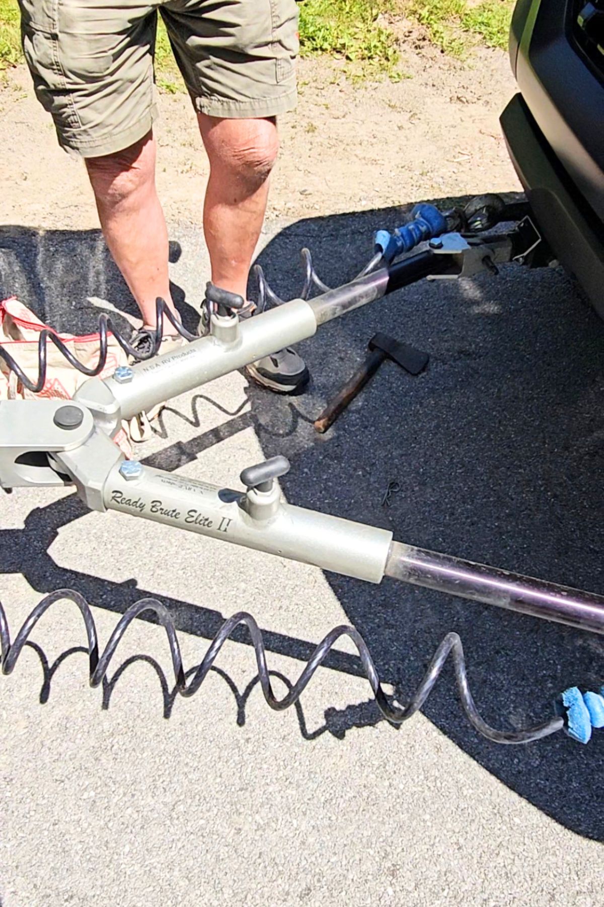 A person stands next to a tow bar labeled "Ready Brute Elite II" attached to a vehicle in Southeast Kansas, with coiled cables extending along the ground.